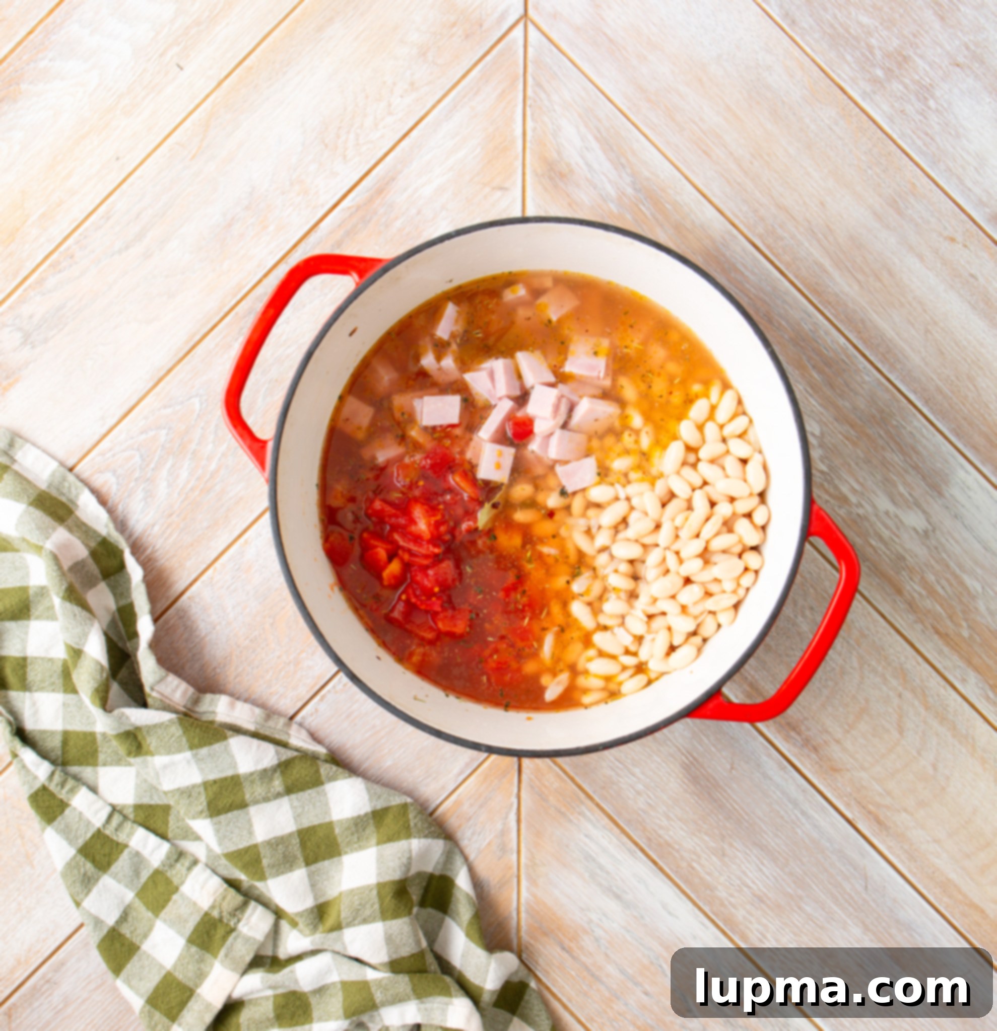 Hearty Navy Bean Soup 8 Diced ham, tomatoes, navy beans, and broth combined in the soup pot, ready for simmering.