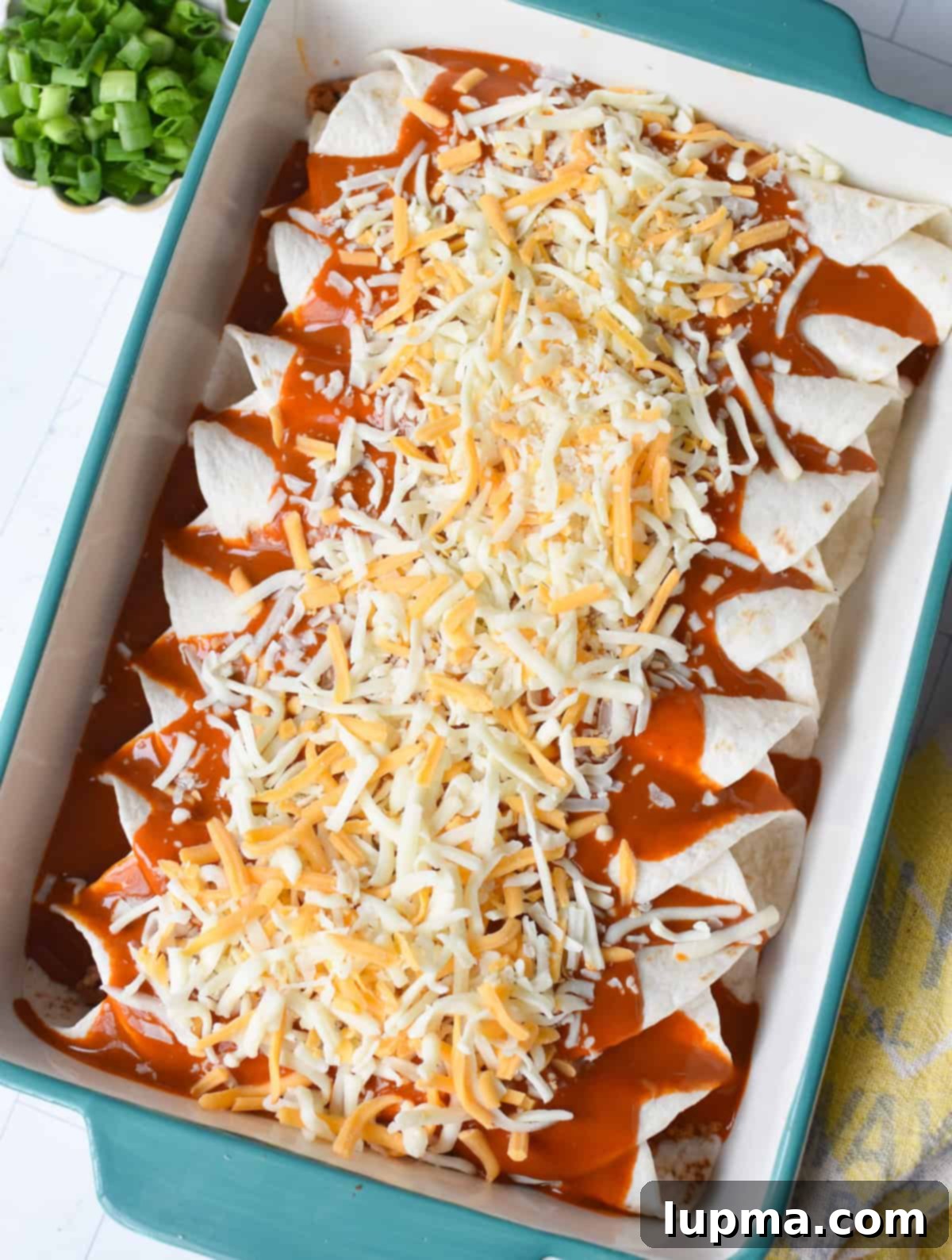 Speedy Pork Enchiladas 6 A casserole dish with rolled enchiladas generously covered in vibrant red enchilada sauce and a sprinkle of shredded cheese, ready for baking.