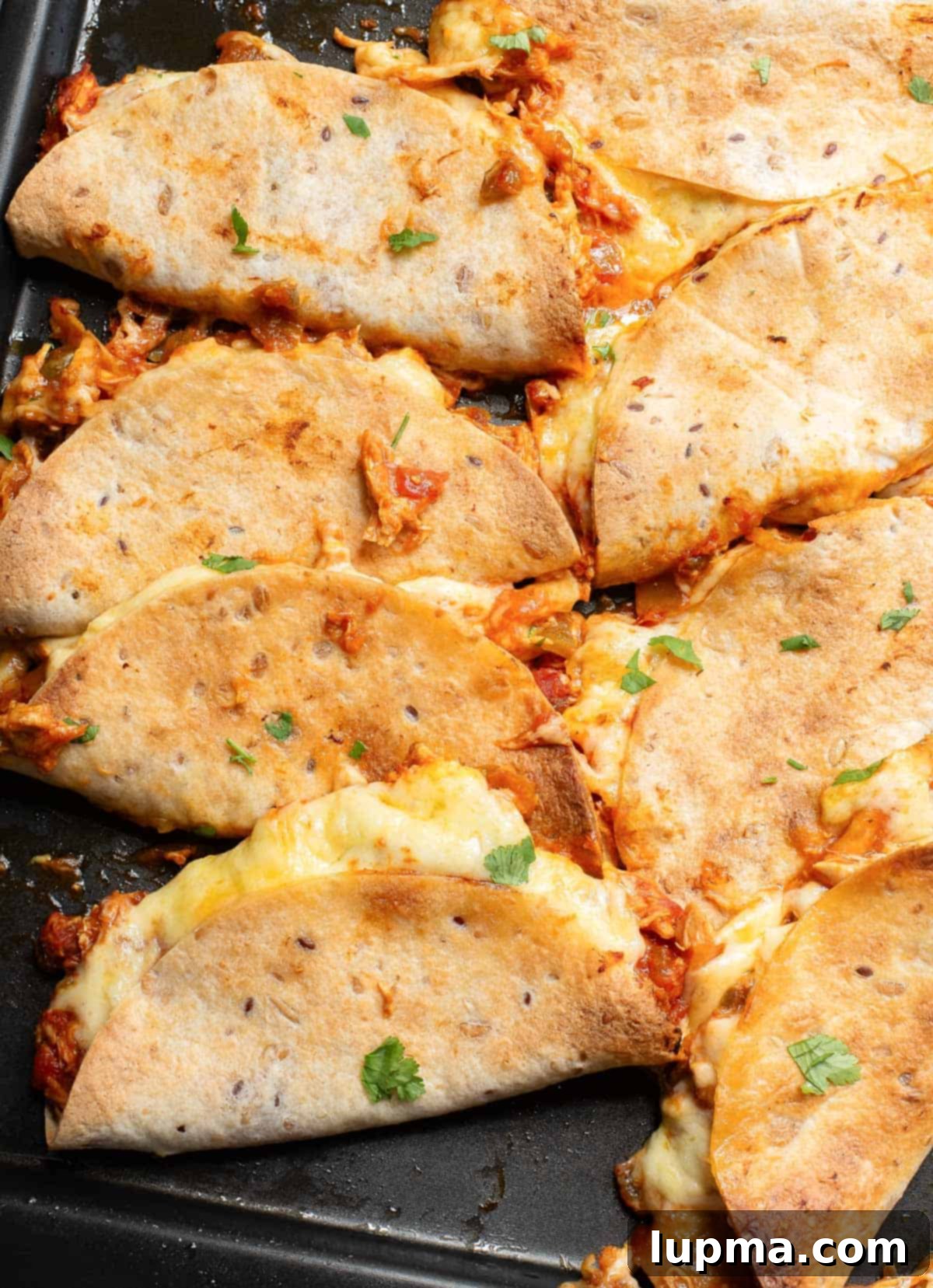 Crispy Baked Chicken Tacos 2 Golden-brown crispy baked chicken tacos on a baking sheet, ready to serve.