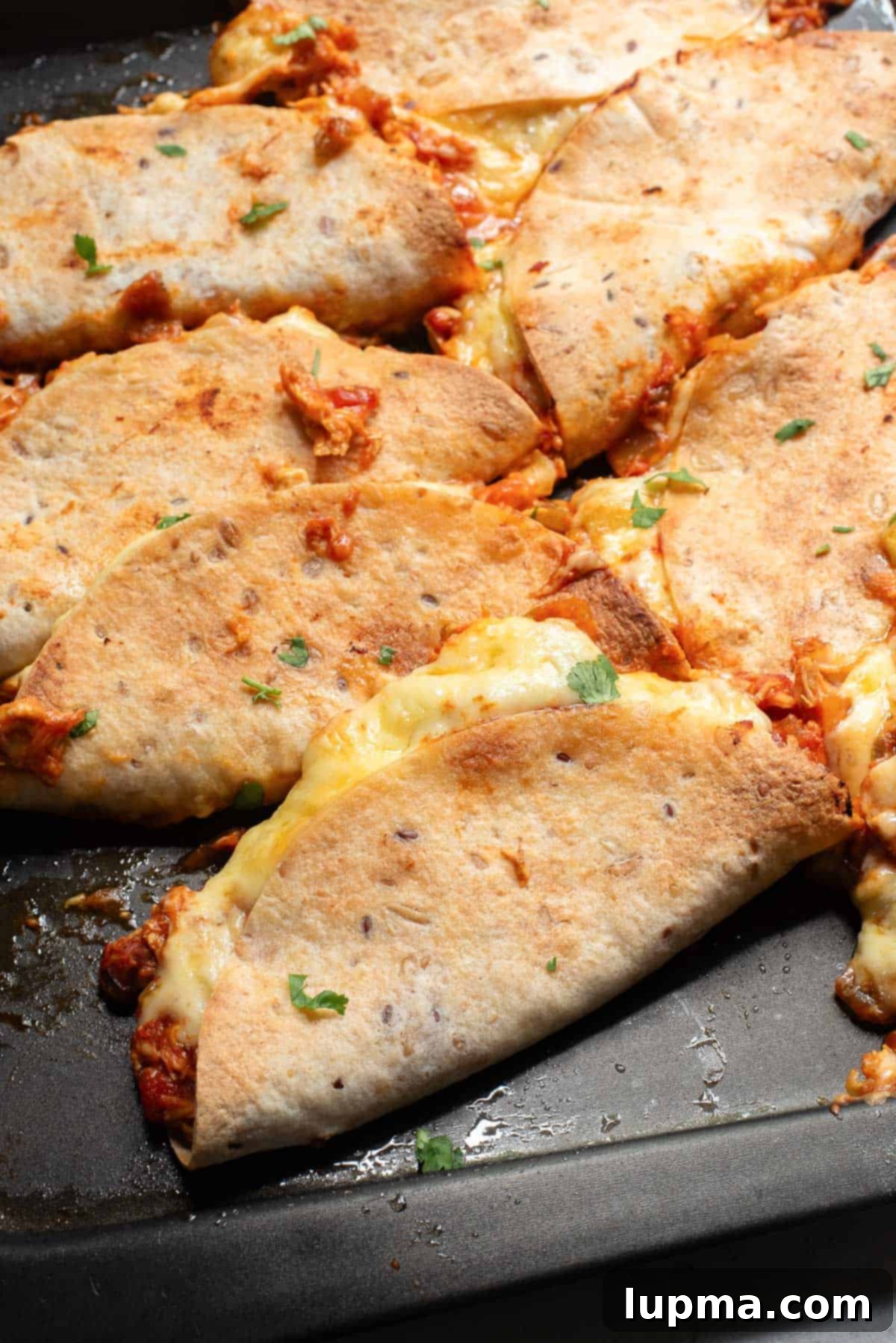 Crispy Baked Chicken Tacos 5 Assembled baked chicken tacos laid out in a single layer on a baking tray before baking.