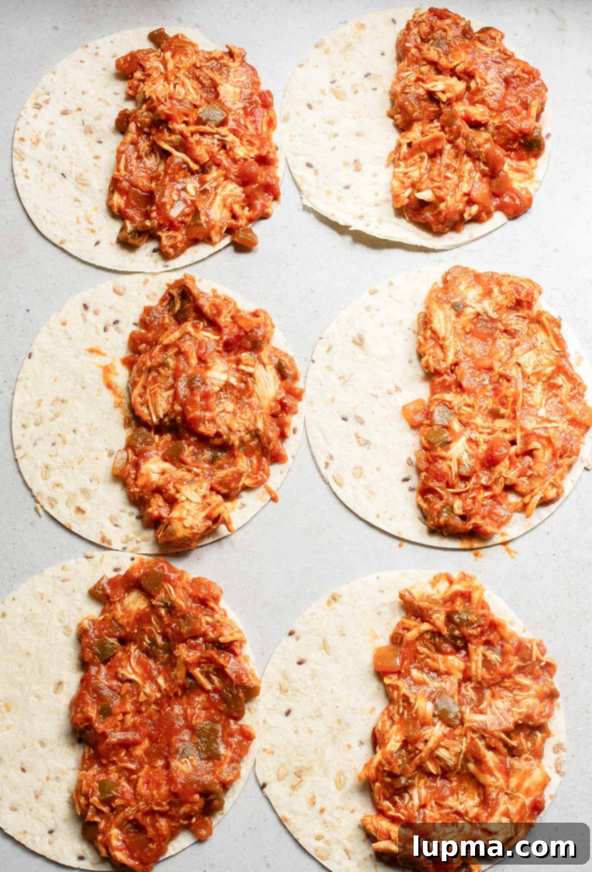 Crispy Baked Chicken Tacos 7 A close-up view of chicken filling and shredded cheese placed on half of a tortilla, ready for folding.