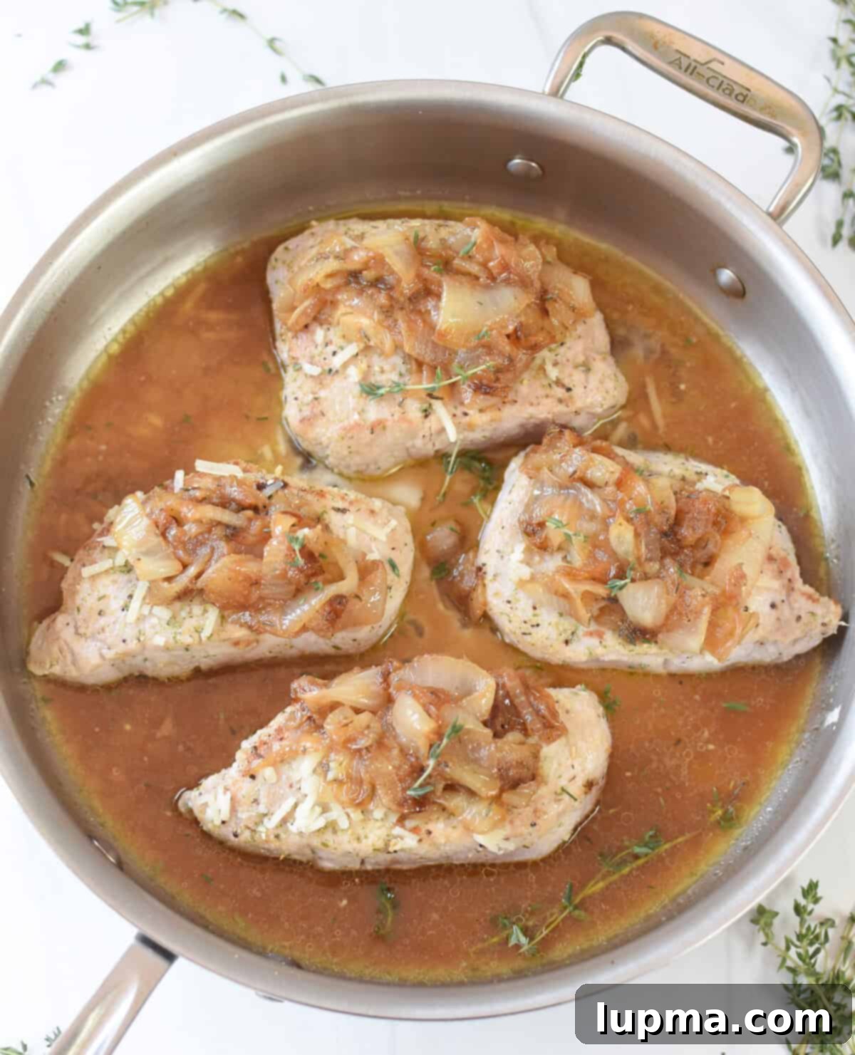 Smothered French Onion Pork Chops 7 French Onion Pork Chops baking in a skillet with melted cheese