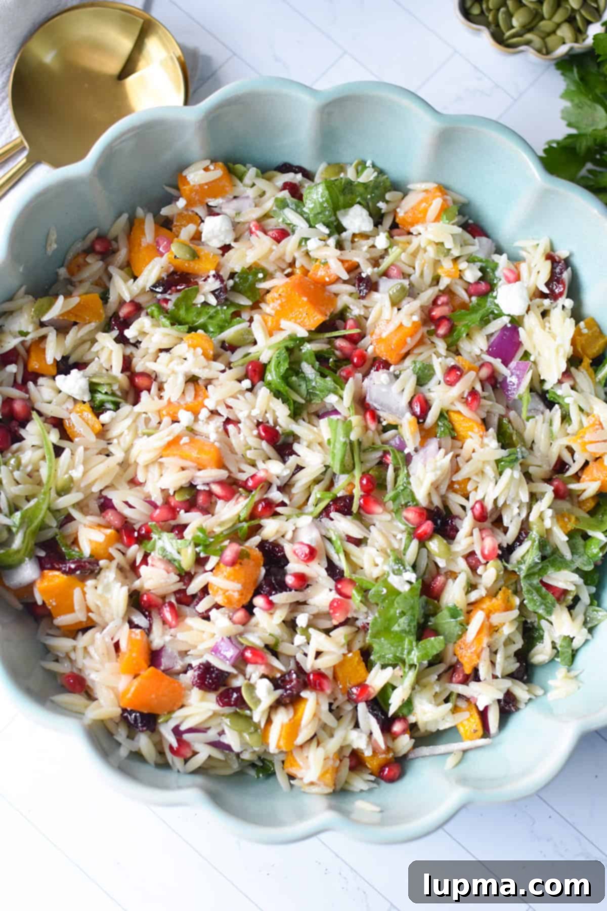 Hearty Autumn Orzo Salad 2 A vibrant Fall Orzo Pasta Salad in a teal bowl, garnished with fresh herbs and golden serving spoons, perfect for autumn entertaining.