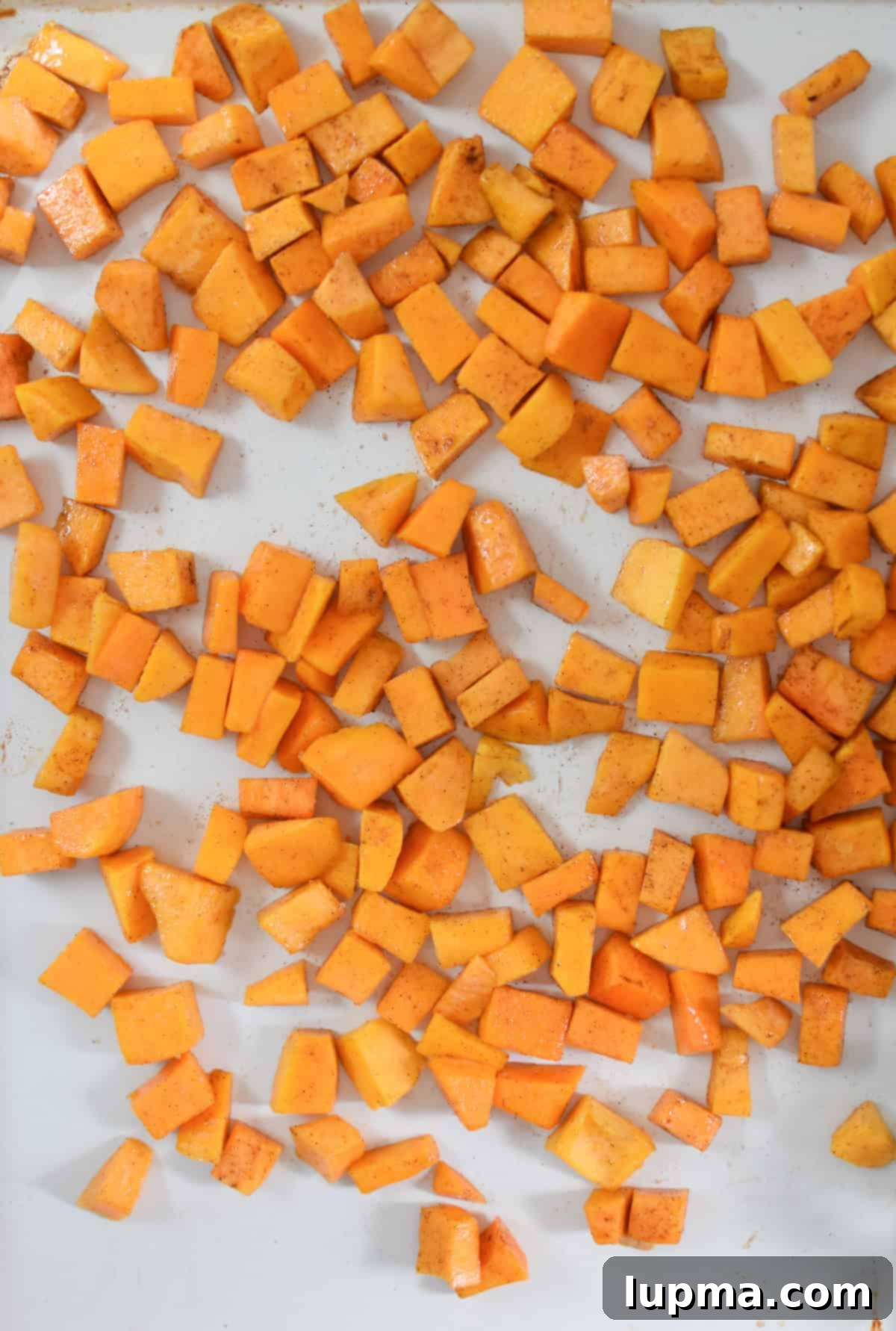 Hearty Autumn Orzo Salad 8 Cubed butternut squash seasoned and spread on a baking sheet, ready for roasting.