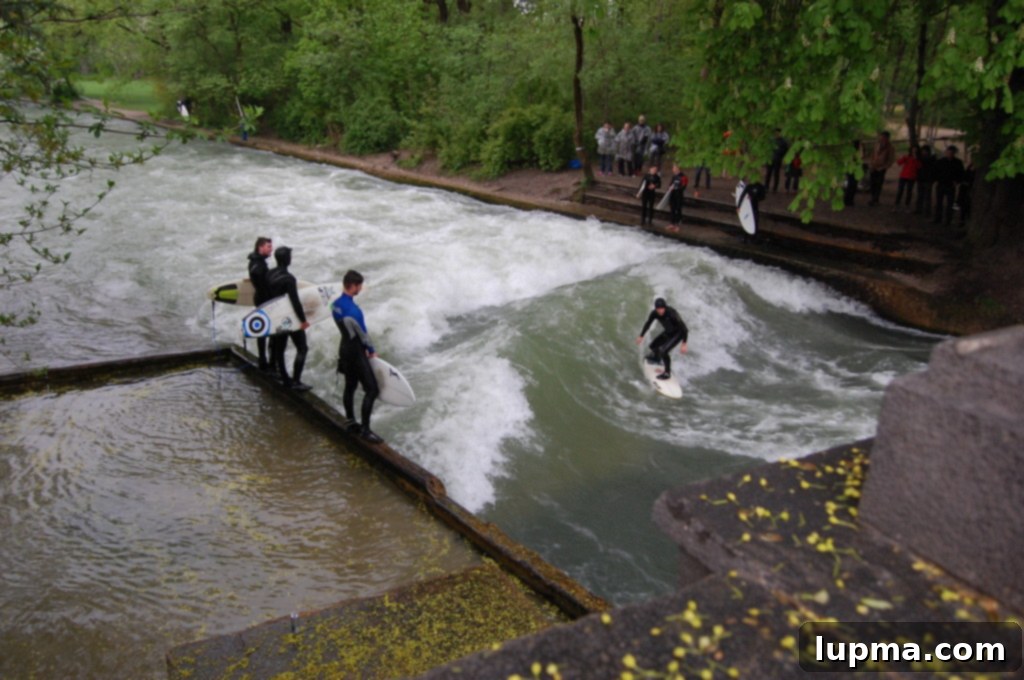 People river surfing on the Eisbach wave in the Englischer Garten, Munich
