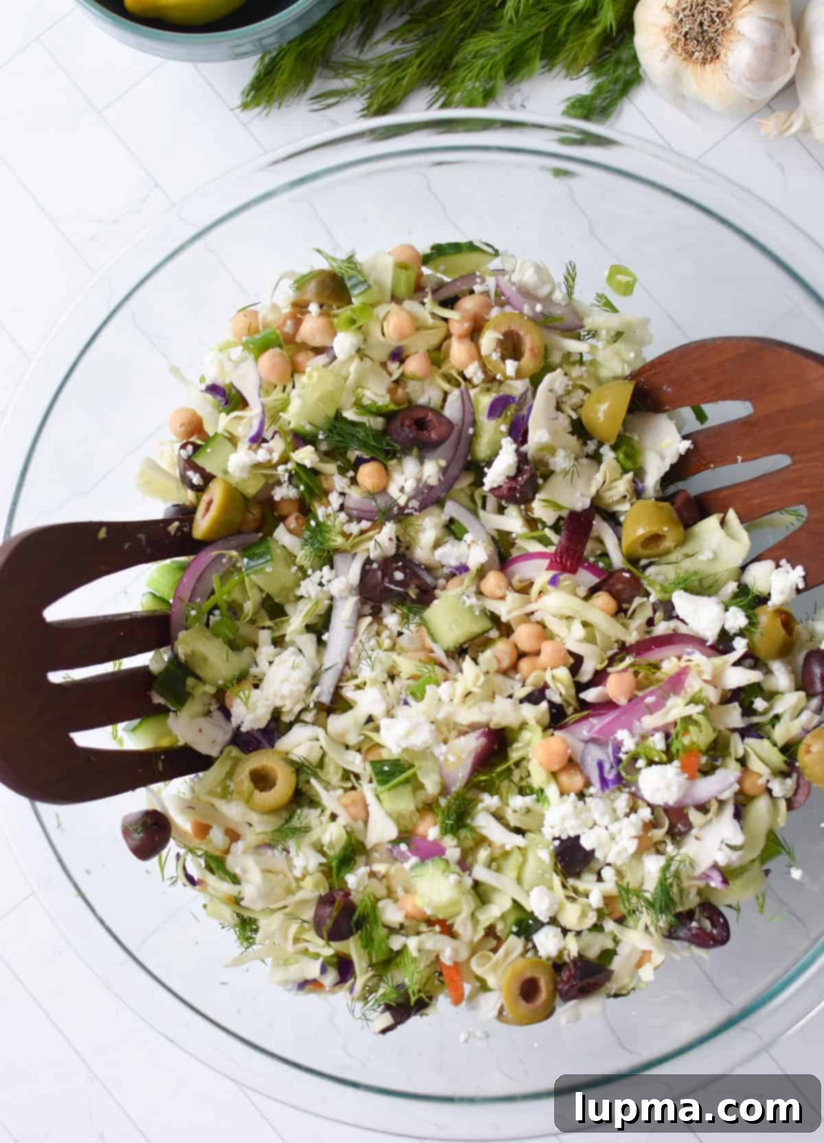 Greek Cabbage Salad mixed in a bowl with dressing being poured.