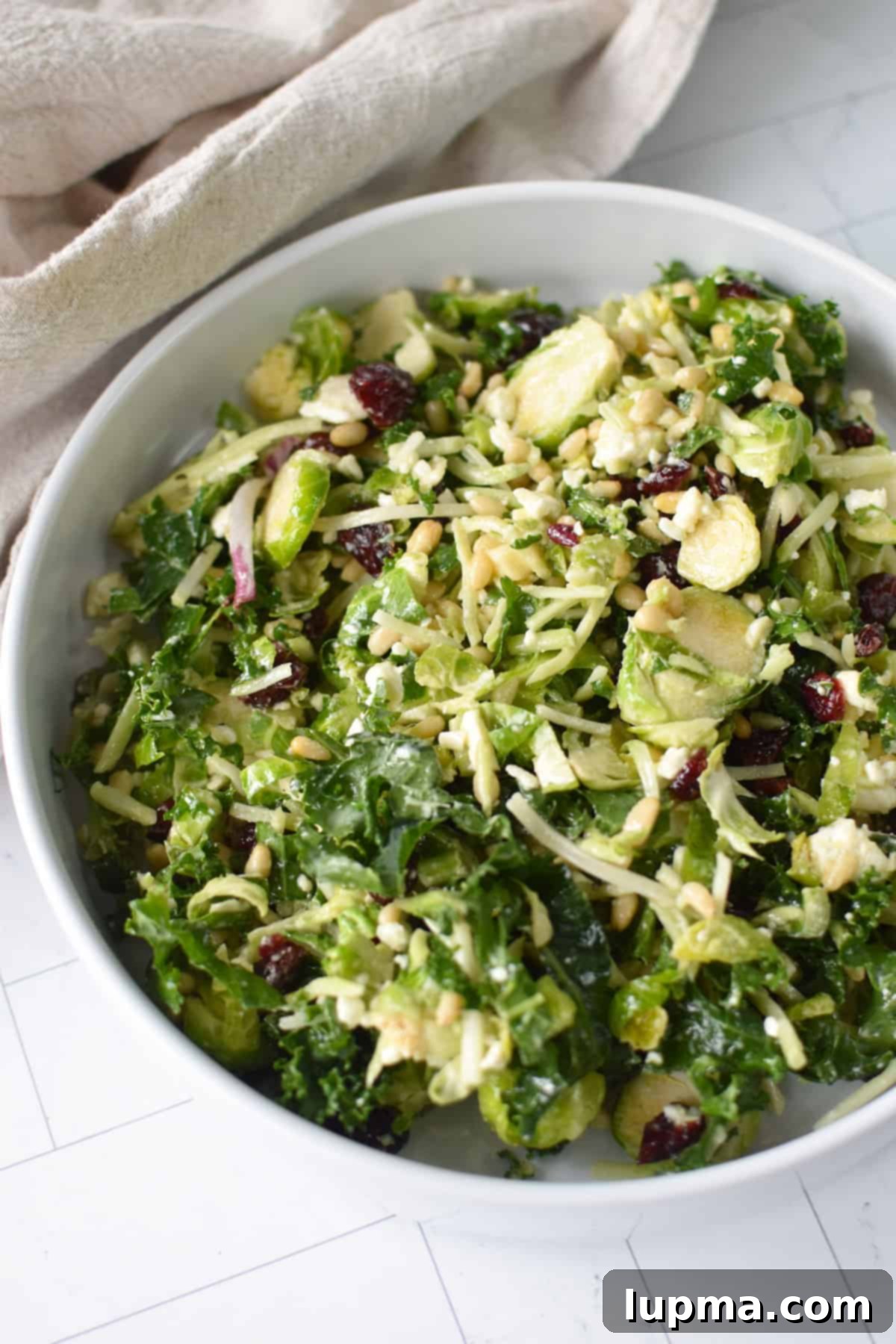 Easy Kale Brussels Sprout Slaw served in a white bowl, garnished and ready to eat