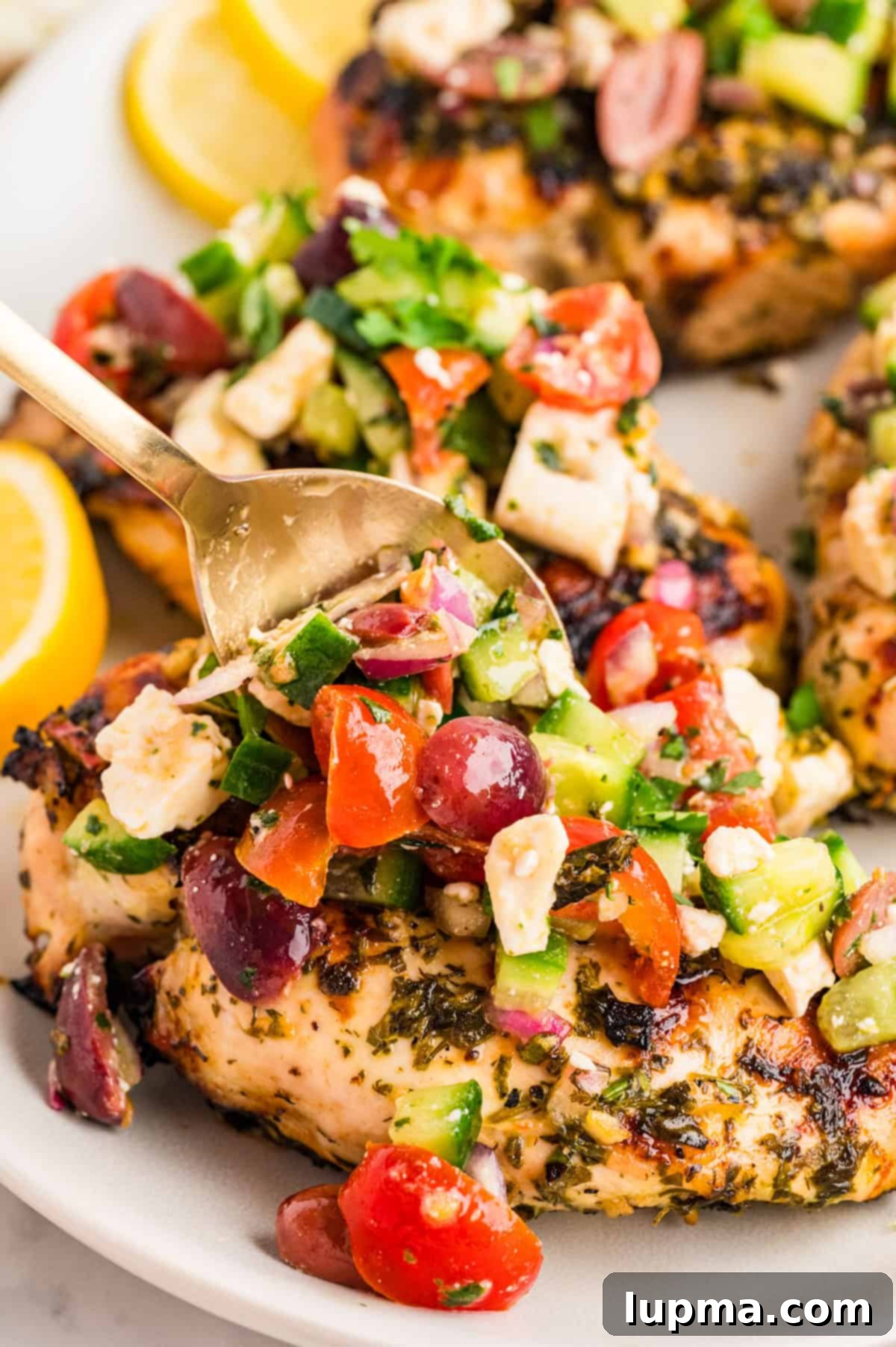 Close-up of the fresh Mediterranean chicken topping with cucumber, cherry tomatoes, Kalamata olives, and feta crumbles.