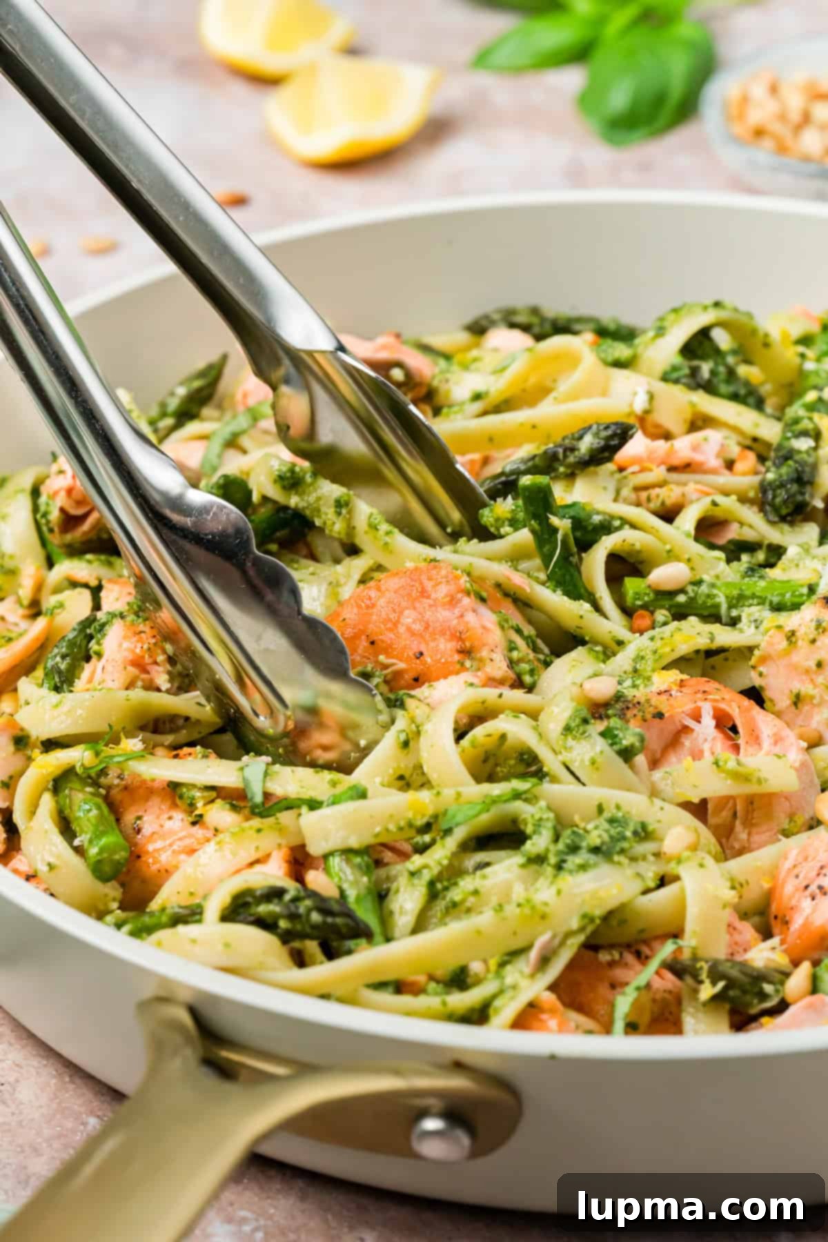 Salmon Pasta with Pesto in a skillet with tongs