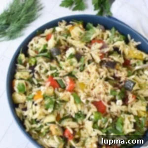 Roasted vegetable orzo salad being served from a blue bowl