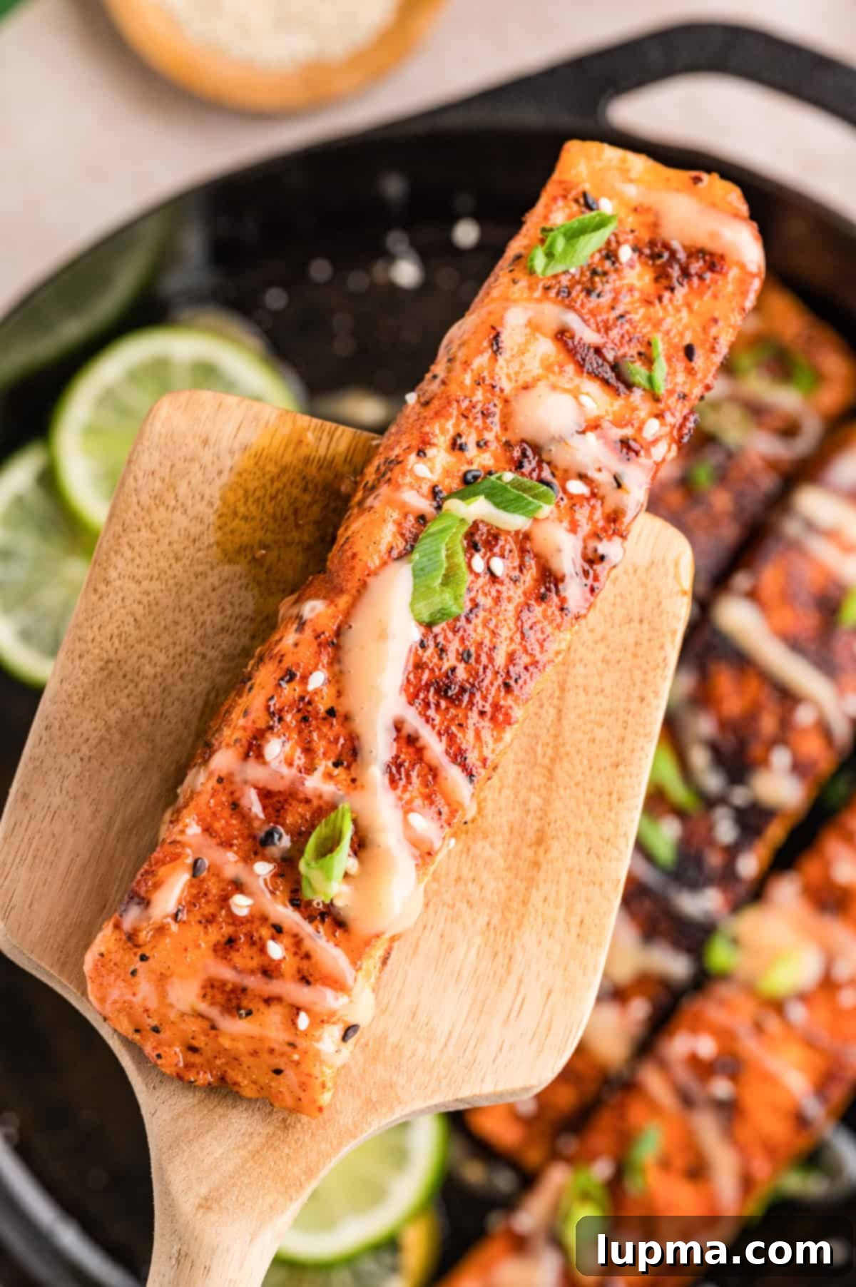 Bang bang salmon with sauce being drizzled over golden seared fillets on a spatula