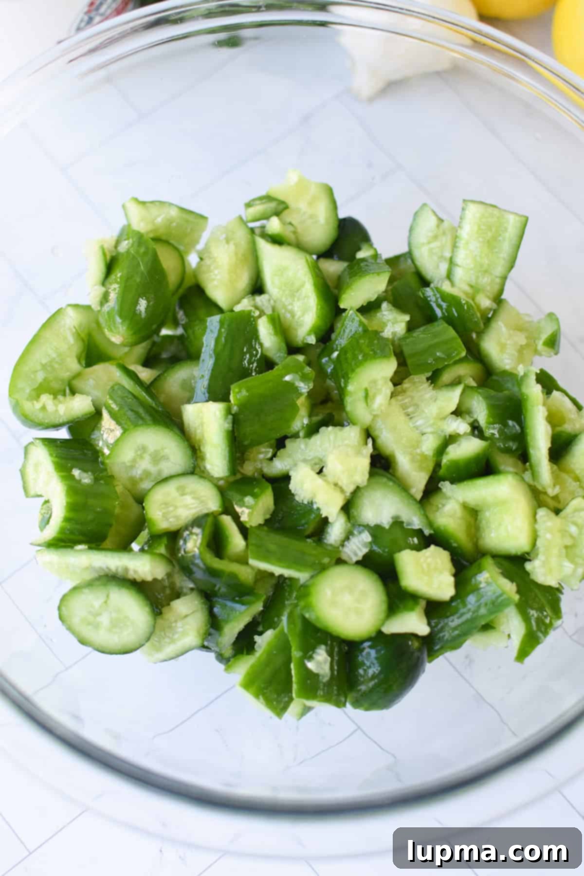 Smashed cucumbers in a colander being salted to drain excess water