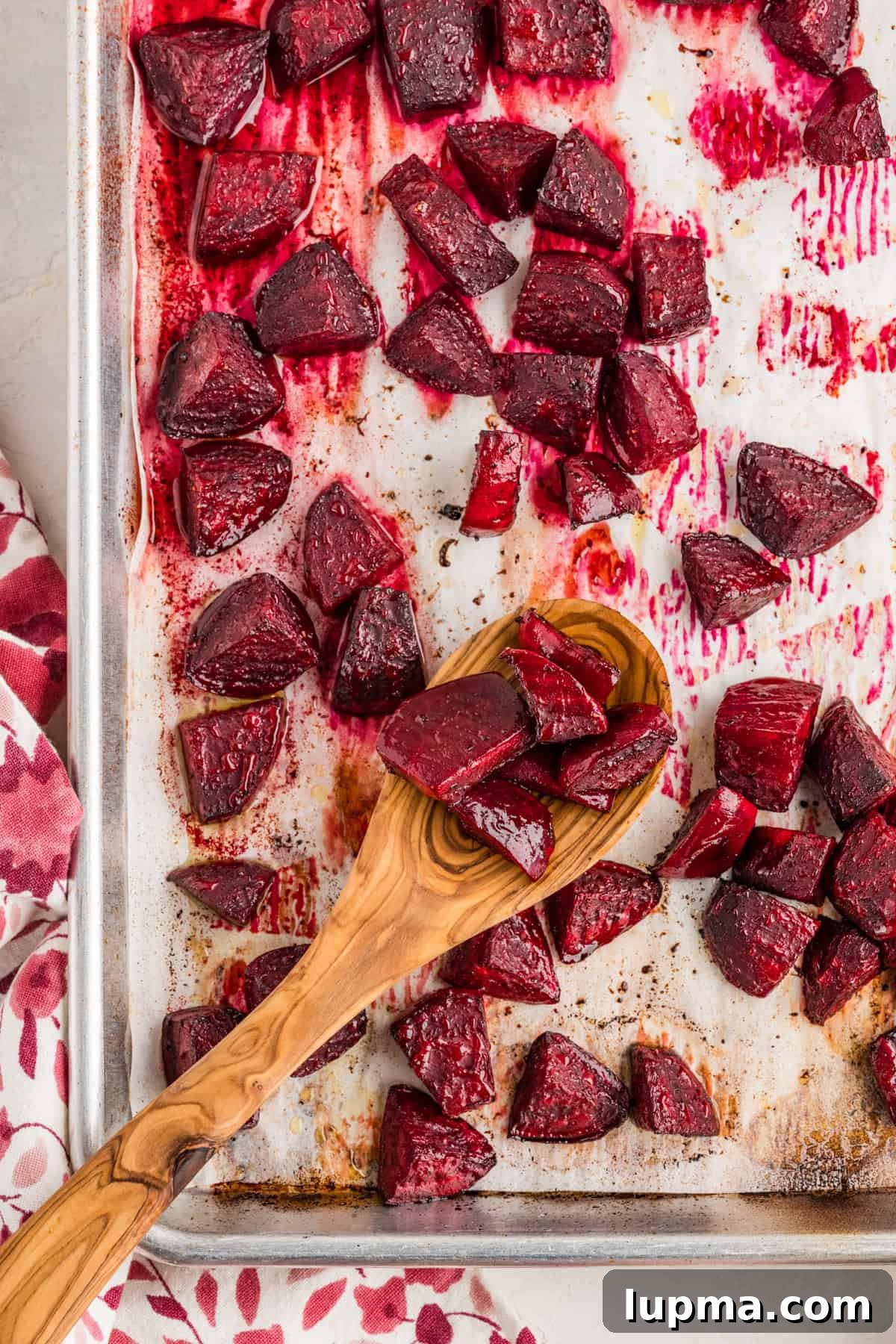 Roasted beets on a baking sheet with a wooden spoon 