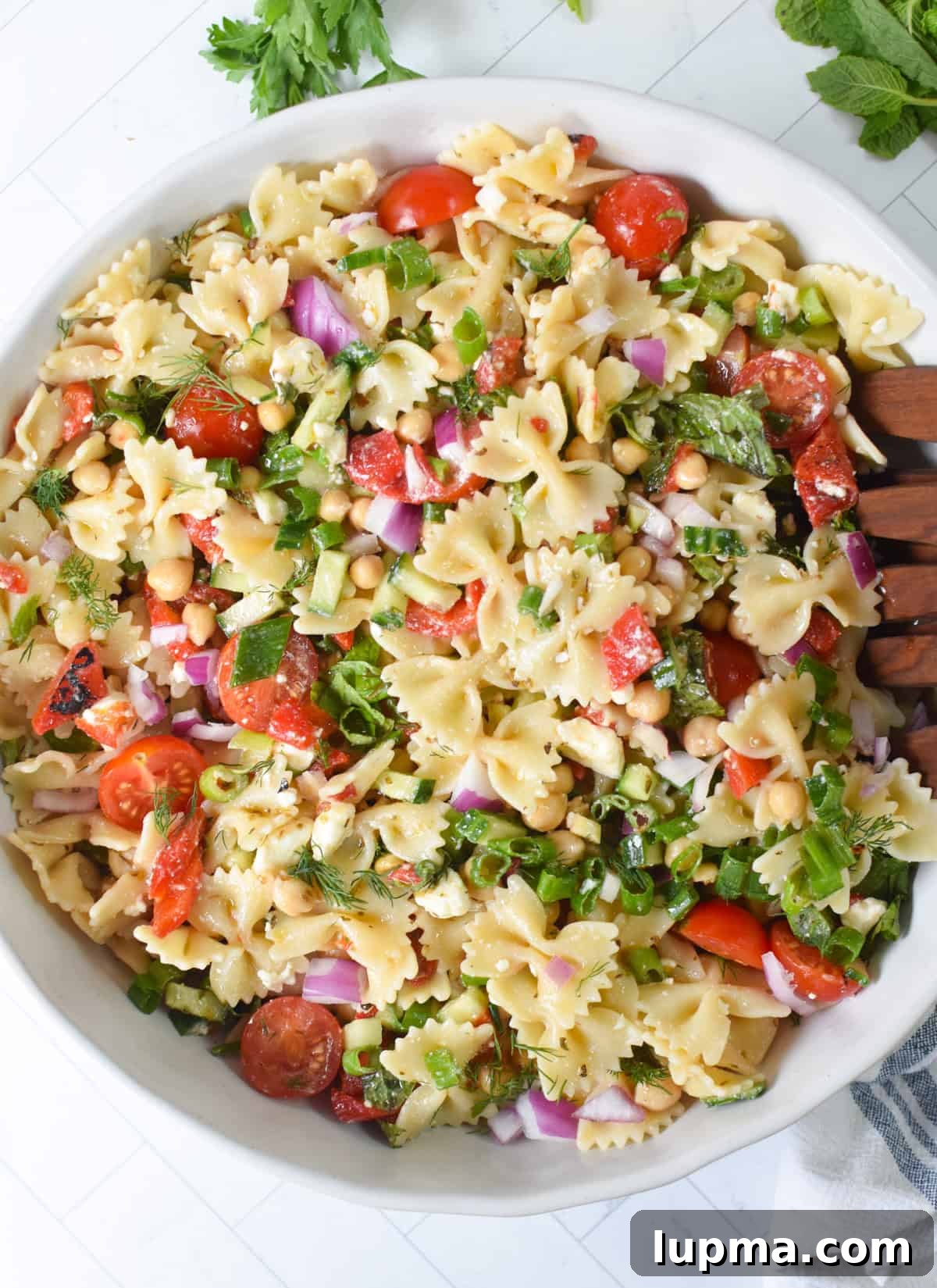 Mediterranean bow tie pasta salad in a large serving bowl with feta and fresh herbs