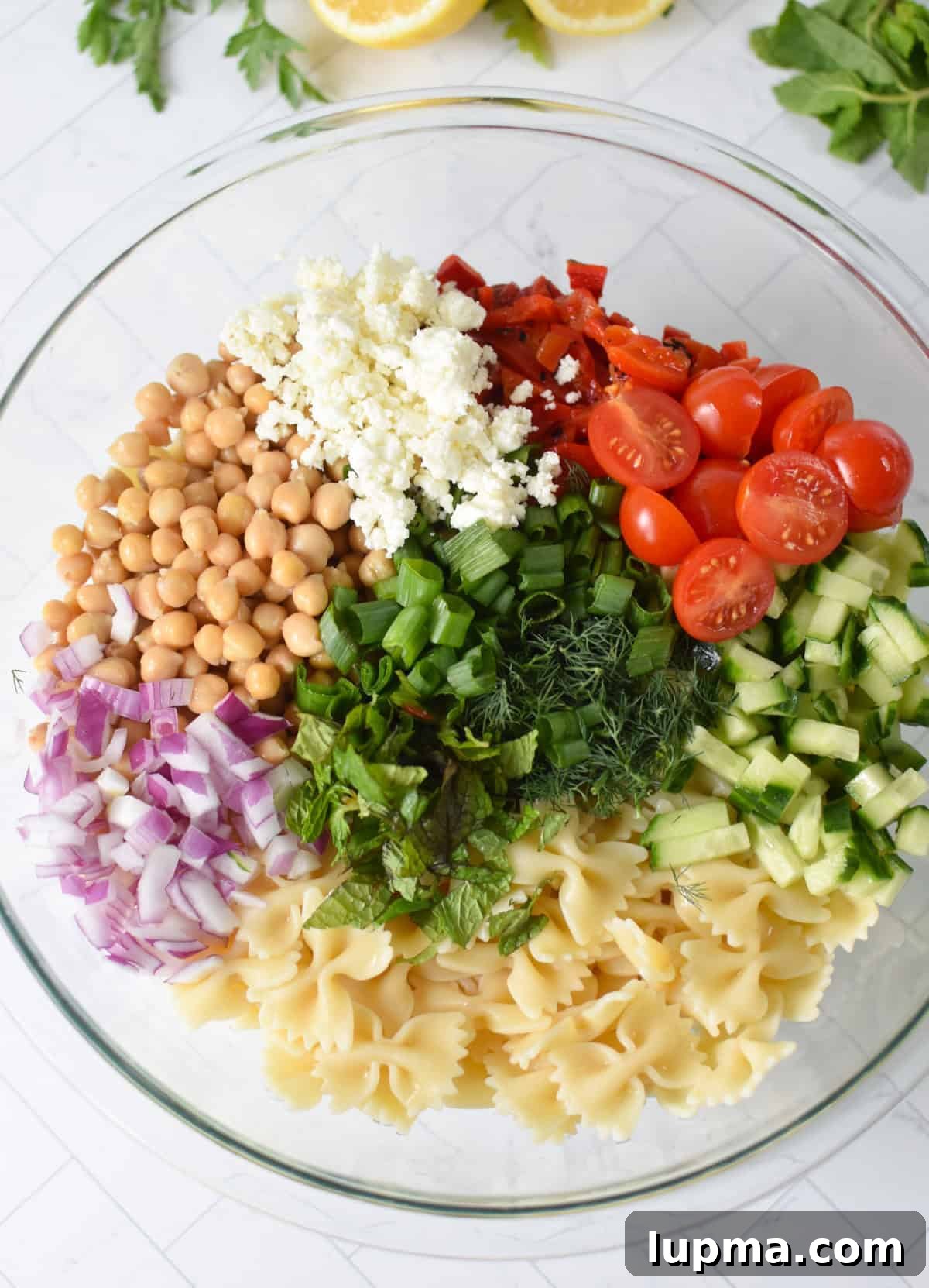 Bow Tie Pasta Salad ingredients in a glass bowl 
