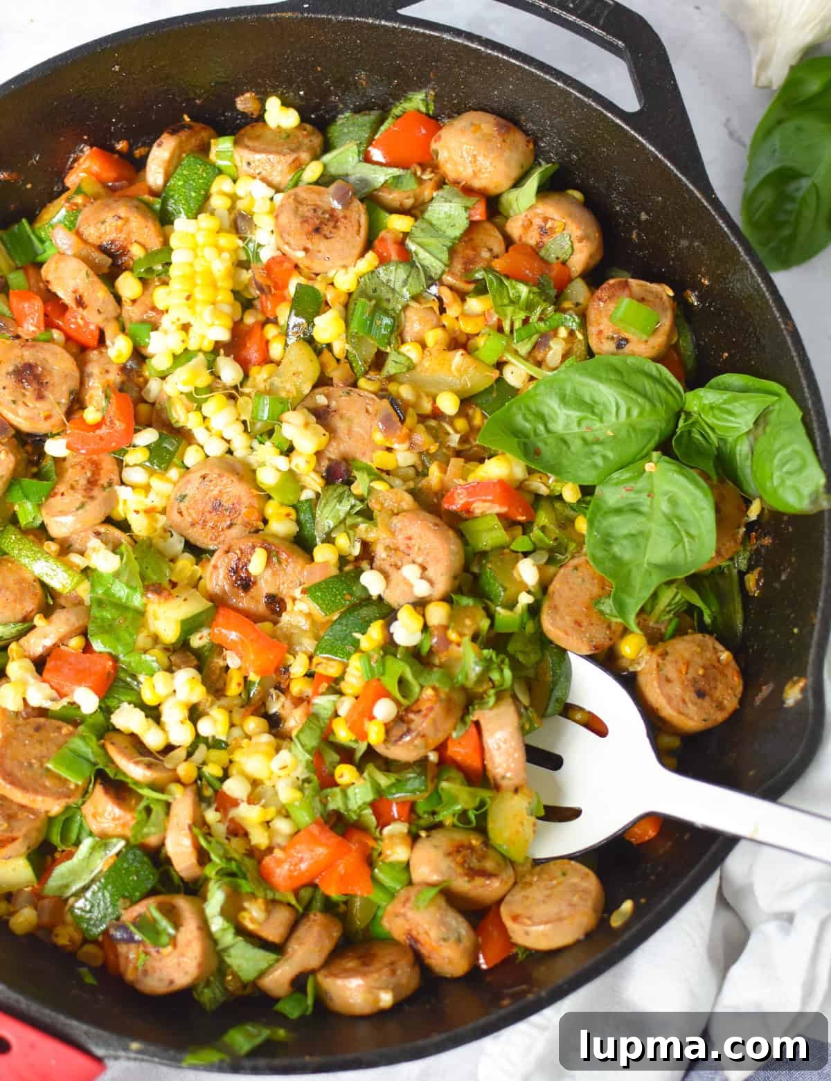 Cast iron skillet of sausage, zucchini, corn, and bell pepper ready to serve