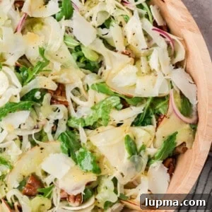 Apple fennel salad with pecans and shaved Parmesan in a tan bowl