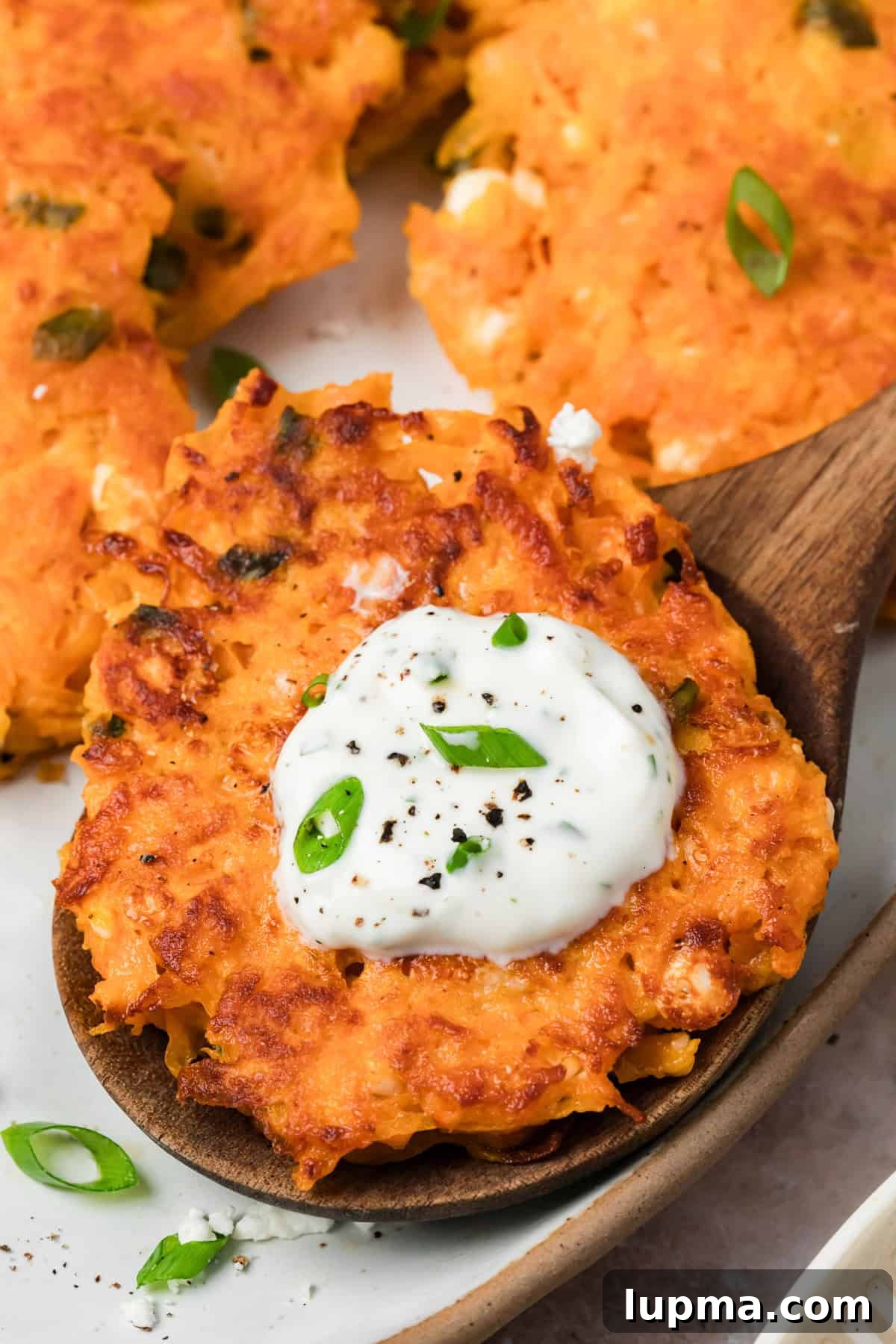 Sweet potato fritters with feta served on a spoon with lemon yogurt sauce