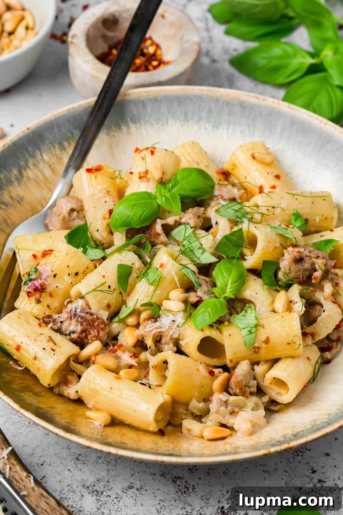 Creamy sausage and fennel pasta on a plate with a fork twirling rigatoni coated in white wine cream sauce